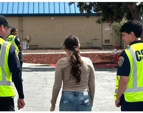 Two Night Walk escorts in neon yellow vests walk with a student through an empty parking lot