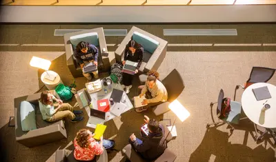 Students are sitting around the table in the library space