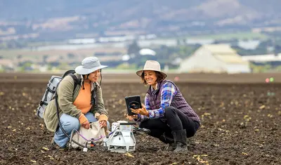 Stefanie Kortman and Elise Vasquez check air samples in local field.