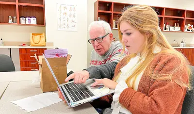 Sophia Capdevila helps Mike Ware identify words from pictures on her laptop