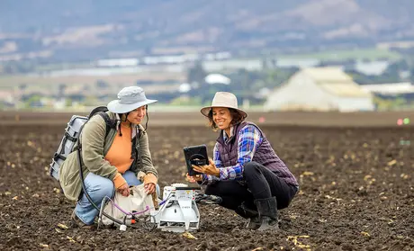 Stefanie Kortman and Elise Vasquez check air samples in local field.